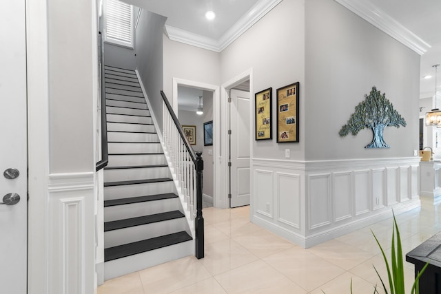 entryway with light tile patterned floors, a decorative wall, a wainscoted wall, ornamental molding, and stairway