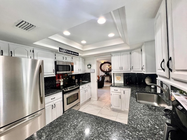 kitchen featuring decorative backsplash, stainless steel appliances, a raised ceiling, sink, and white cabinetry