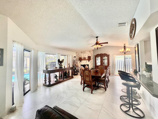 dining space with a fireplace, ceiling fan with notable chandelier, vaulted ceiling, and a textured ceiling