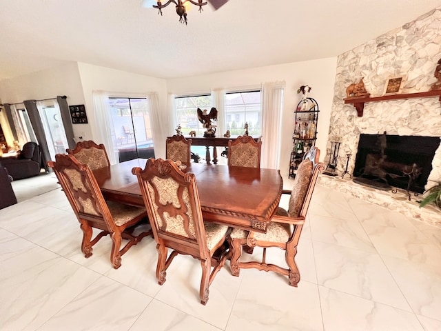 dining space with a stone fireplace and vaulted ceiling