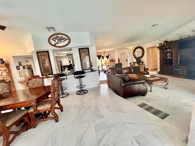 living room featuring a notable chandelier, lofted ceiling, and a textured ceiling