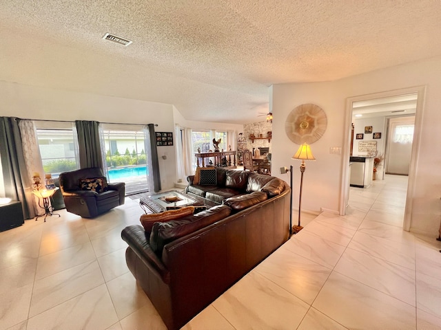 tiled living room with ceiling fan and a textured ceiling