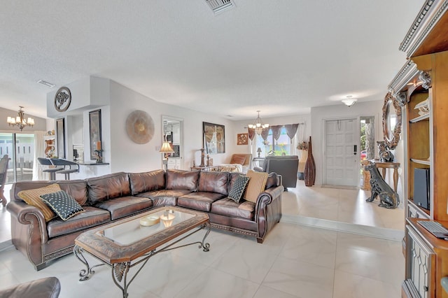 living room with a notable chandelier, light tile patterned floors, and a textured ceiling