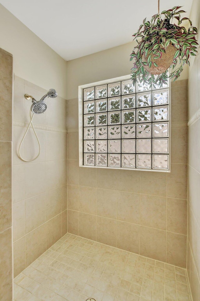 bathroom with tiled shower and a healthy amount of sunlight