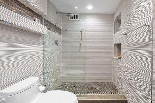 bathroom featuring a tile shower and toilet