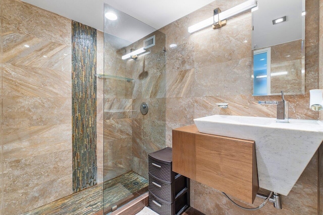 bathroom with tile walls, tiled shower, and vanity