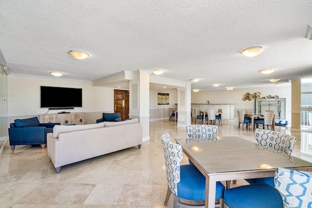 dining room with ornamental molding, decorative columns, and a textured ceiling