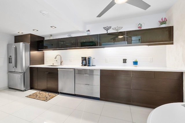 kitchen featuring stainless steel appliances, sink, light tile patterned flooring, backsplash, and dark brown cabinets