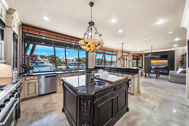 kitchen with dark stone counters, stainless steel appliances, crown molding, a water view, and an island with sink