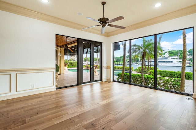 unfurnished room featuring ceiling fan, french doors, crown molding, wood-type flooring, and a water view