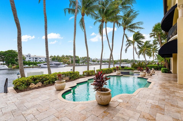 view of pool with a patio area, a water view, and an in ground hot tub