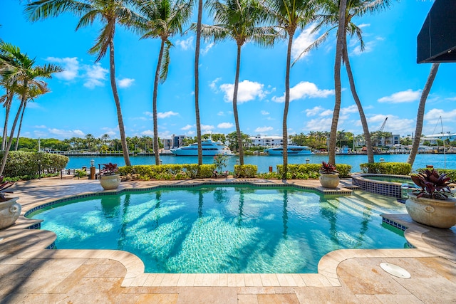 view of pool with an in ground hot tub and a water view