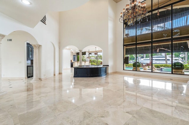 interior space with a high ceiling, decorative columns, and a notable chandelier