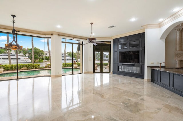 unfurnished living room featuring a wealth of natural light, ornamental molding, and ceiling fan