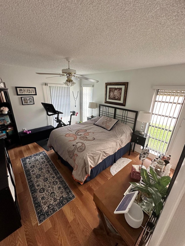 bedroom with ceiling fan, wood-type flooring, and a textured ceiling