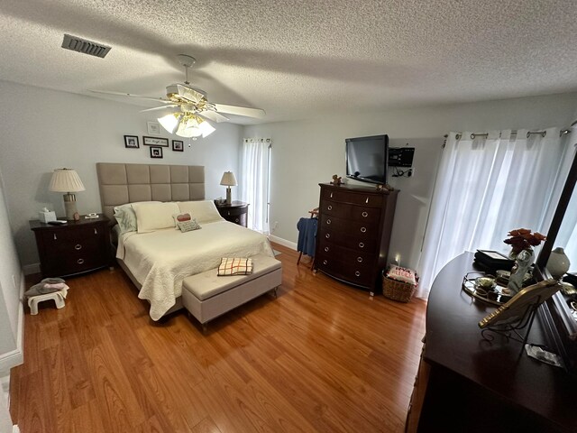 bedroom featuring wood-type flooring, ceiling fan, and a textured ceiling