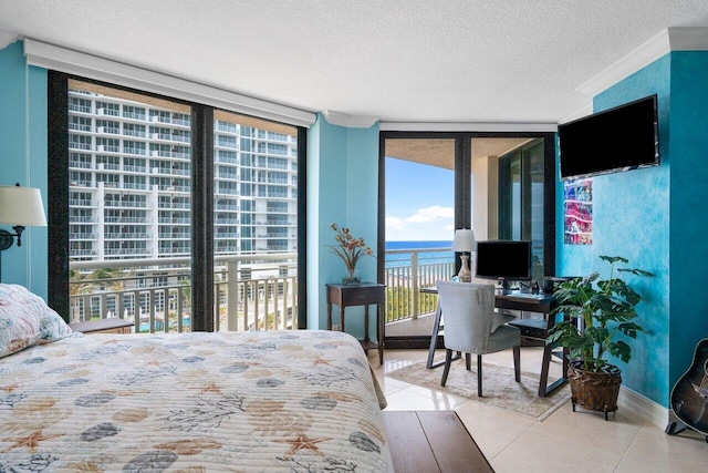 bedroom with a water view, a textured ceiling, a wall of windows, and access to outside