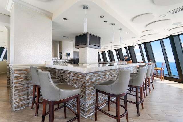 kitchen with decorative light fixtures, a kitchen bar, expansive windows, and kitchen peninsula