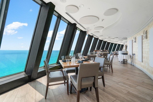 dining area with a wealth of natural light, a water view, and light hardwood / wood-style floors