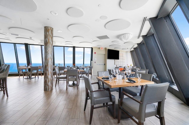 dining room with hardwood / wood-style floors, a water view, and expansive windows