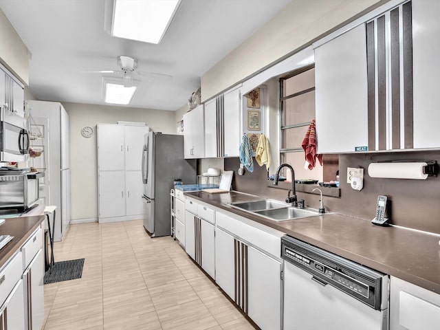 kitchen featuring stainless steel appliances, white cabinets, sink, ceiling fan, and light tile floors