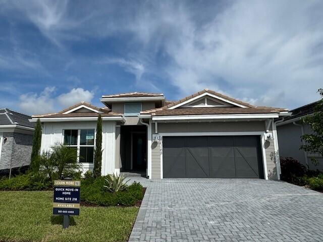 view of front of property featuring a front yard, decorative driveway, and a garage
