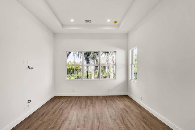 spare room featuring visible vents, baseboards, wood finished floors, recessed lighting, and a raised ceiling