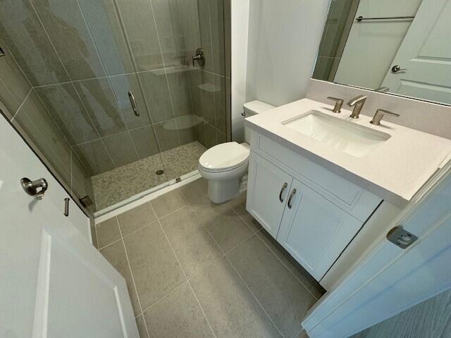 bathroom featuring tile patterned flooring, vanity, toilet, and an enclosed shower