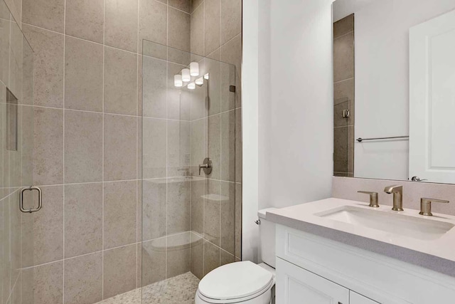 bathroom featuring vanity, a shower with door, and toilet