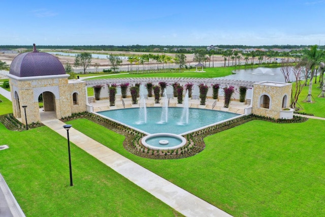 view of pool with exterior fireplace, a water view, and a yard