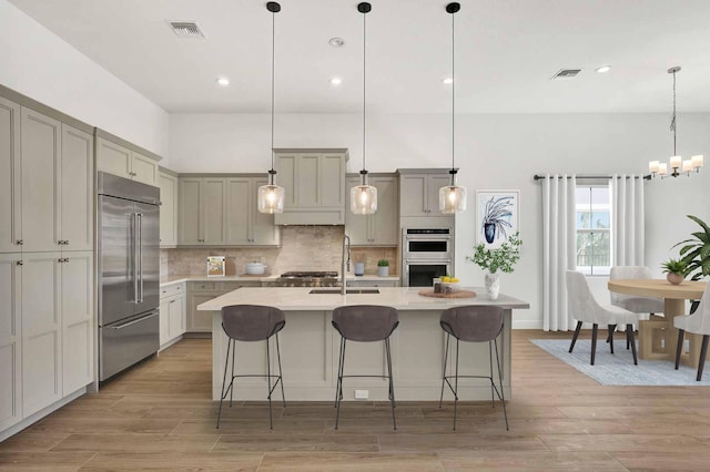 kitchen featuring light countertops, tasteful backsplash, light wood-type flooring, a sink, and appliances with stainless steel finishes