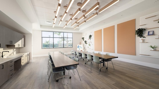 dining room with a raised ceiling, visible vents, baseboards, and wood finished floors