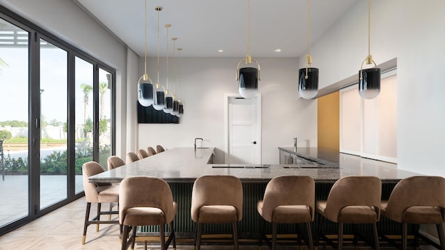 kitchen featuring a breakfast bar, hanging light fixtures, dark stone countertops, kitchen peninsula, and light parquet floors