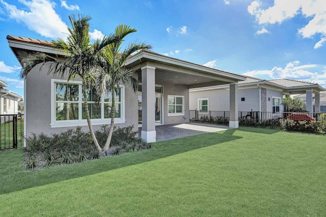 back of house with fence, a tiled roof, stucco siding, a yard, and a patio area