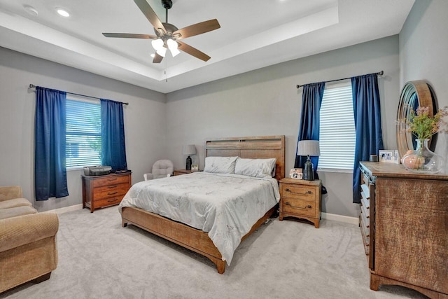 carpeted bedroom featuring ceiling fan and a tray ceiling