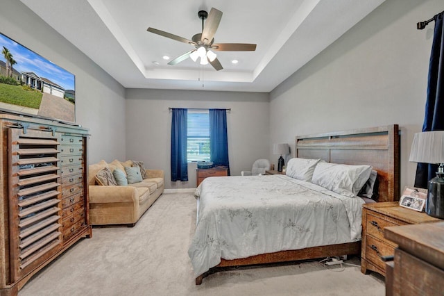 carpeted bedroom with ceiling fan and a raised ceiling