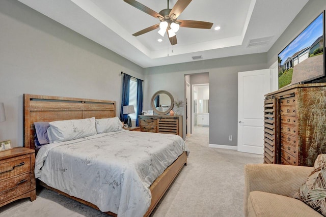 bedroom featuring light carpet, connected bathroom, ceiling fan, and a raised ceiling