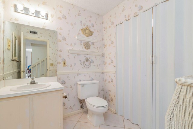 bathroom featuring a textured ceiling, oversized vanity, toilet, and tile floors