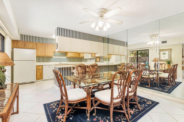 tiled dining area featuring a textured ceiling and ceiling fan