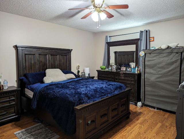 bedroom with ceiling fan, a textured ceiling, and hardwood / wood-style floors