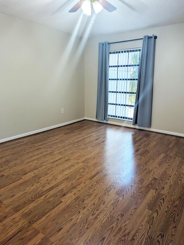 empty room with ceiling fan, dark hardwood / wood-style flooring, and a textured ceiling