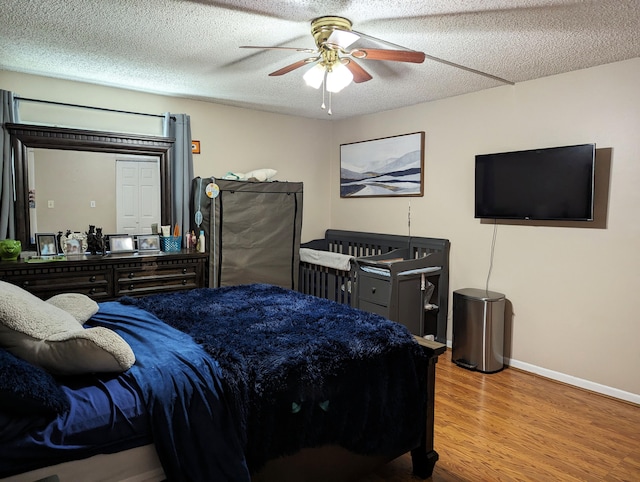 bedroom featuring a textured ceiling, stainless steel refrigerator, ceiling fan, and light hardwood / wood-style floors