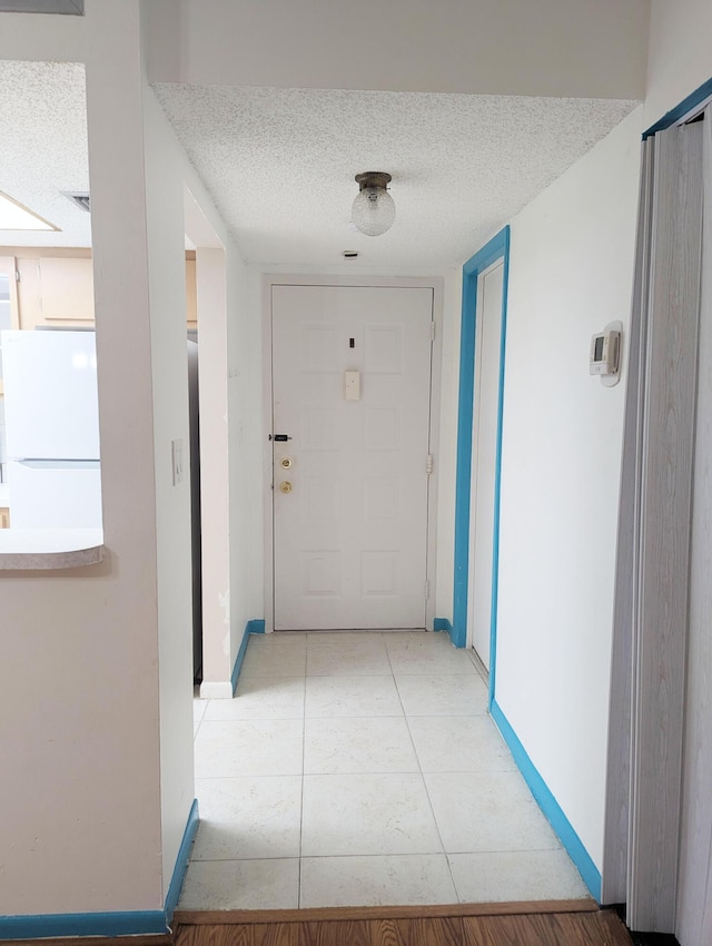 hall with light tile patterned floors and a textured ceiling