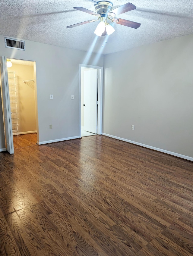 unfurnished room featuring ceiling fan, dark hardwood / wood-style flooring, and a textured ceiling