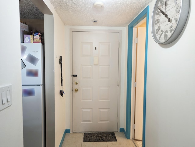 doorway featuring a textured ceiling and light tile patterned floors