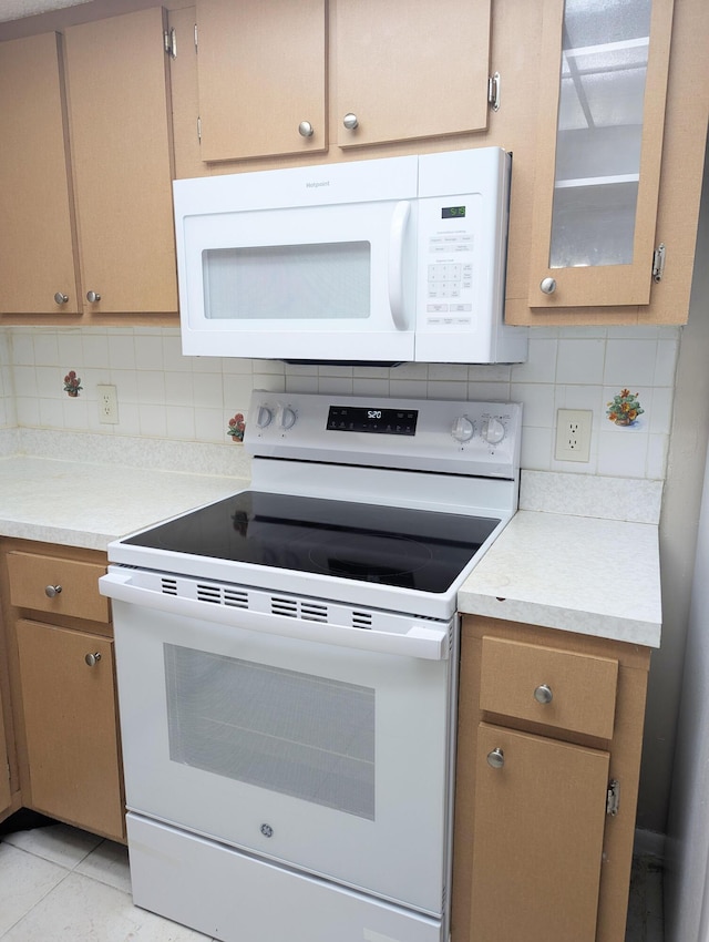 kitchen with light tile patterned floors, white appliances, and decorative backsplash