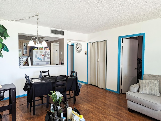 dining space featuring a textured ceiling, an inviting chandelier, and hardwood / wood-style flooring