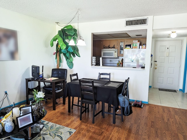 dining area with wood-type flooring and a textured ceiling