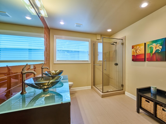 bathroom with toilet, a shower with door, and vanity