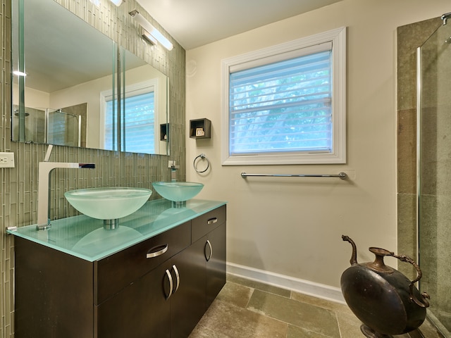 bathroom featuring a shower with door, vanity, backsplash, and plenty of natural light